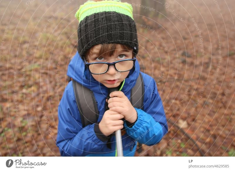 face of a beautiful child, wearing glasses,looking  up and holding a stick Stress Frustration Fear of the future Bans Grimace communication problem distressed