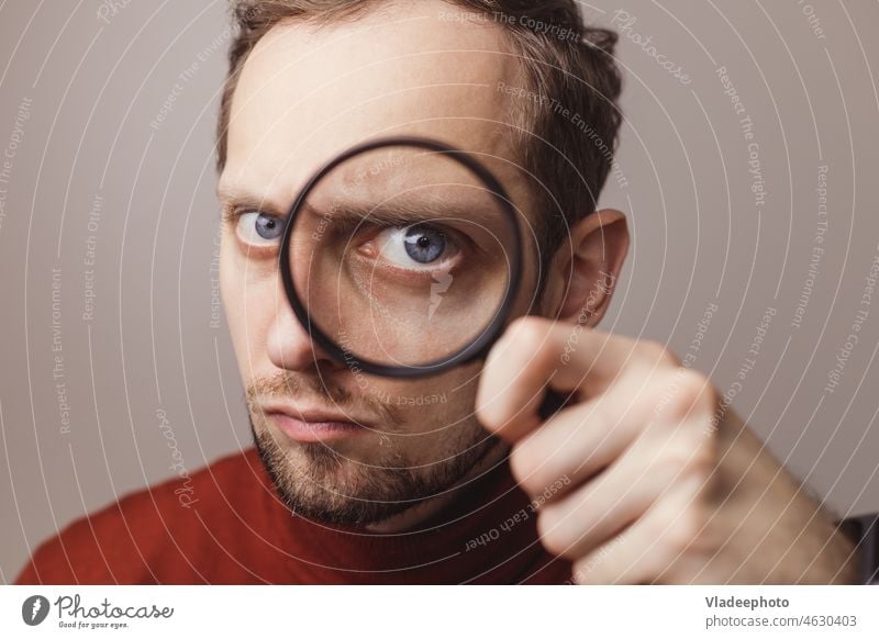 The man looking through a magnifier with suspicious business caucasian eye lens surprise search magnifying loupe businessman glass concept young detective adult