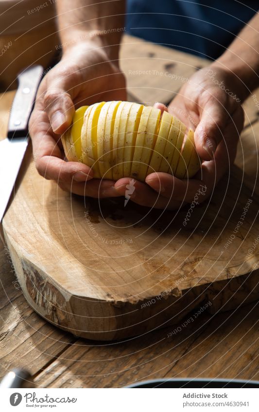 Faceless man showing sliced potato cook culinary cuisine kitchen vegetable raw hasselback food product ingredient gastronomy home cutting board prepare lunch