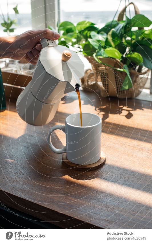 Anonymous person pouring coffee from moka pot caffeine beverage hot drink refreshment kitchen morning table home tasty apartment transparent light fragrant