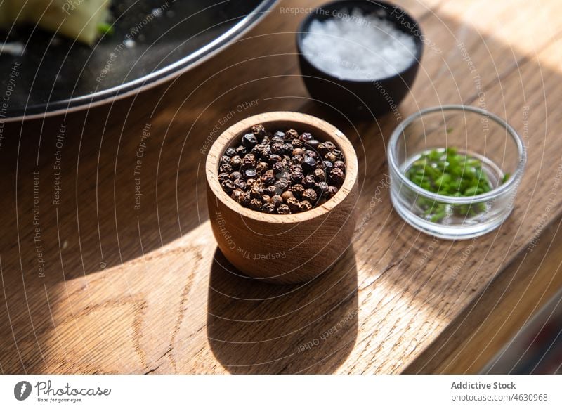 Bowl with peppercorns on table spice condiment flavoring kitchen spicy ingredient seasoning culinary bowl salt wooden cuisine home sunlight surface sunshine