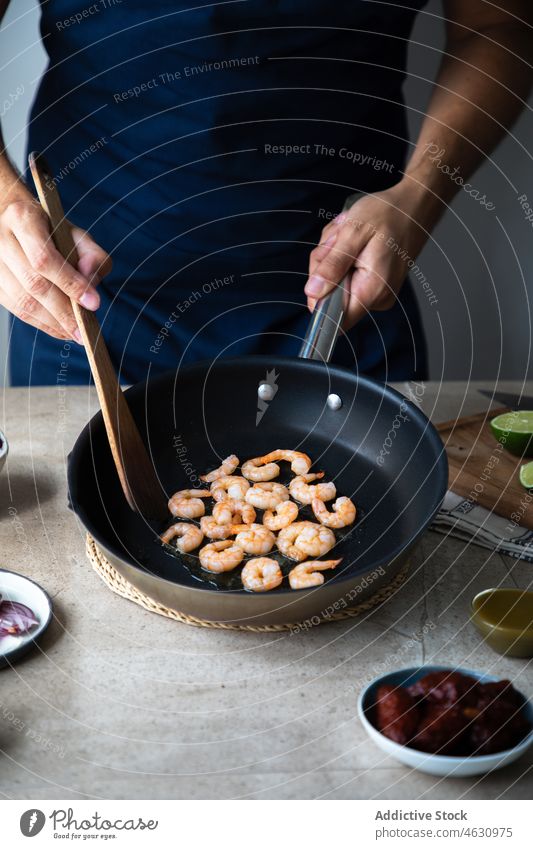 Anonymous man frying shrimps in pan frying pan cook culinary cuisine ingredient kitchen seafood recipe raw chef prepare product table gastronomy home fresh