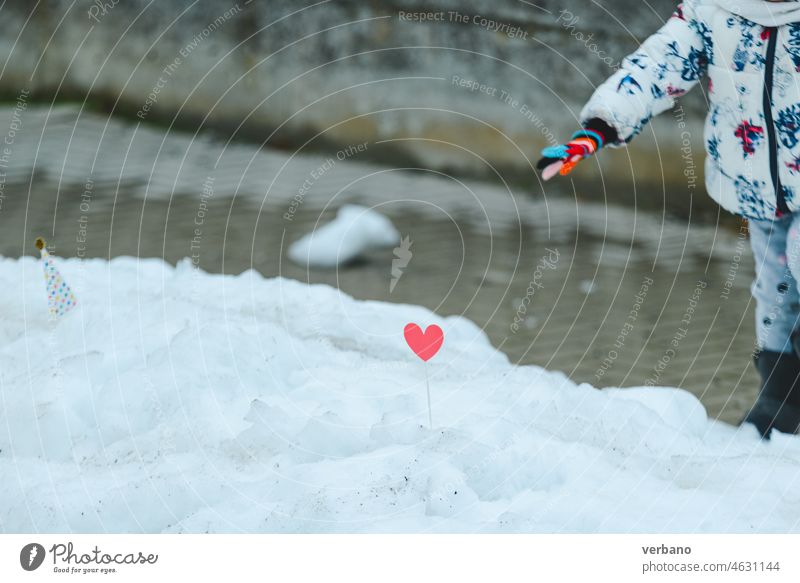 child picking a heart shaped toy in the snow winter cold love white season girl holiday childhood nature fun kid people christmas snowy beautiful happiness