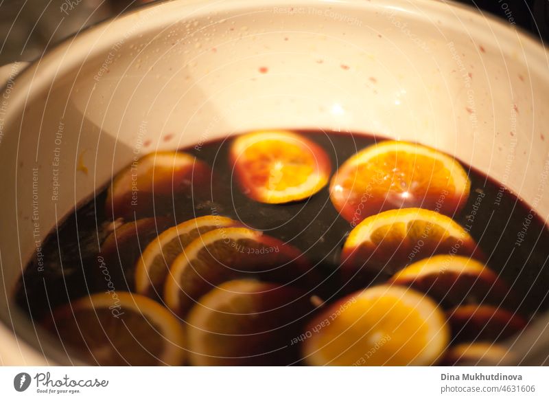 Making mulled wine - putting sliced oranges in a pot with red wine. Homemade mulled wine preparation alcohol making punch seasoning kitchen mix menu december