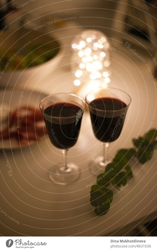 Two glasses of red wine with appetizers on a romantic candlelight date with festive lights drink alcohol table white restaurant wineglass bottle beverage dinner