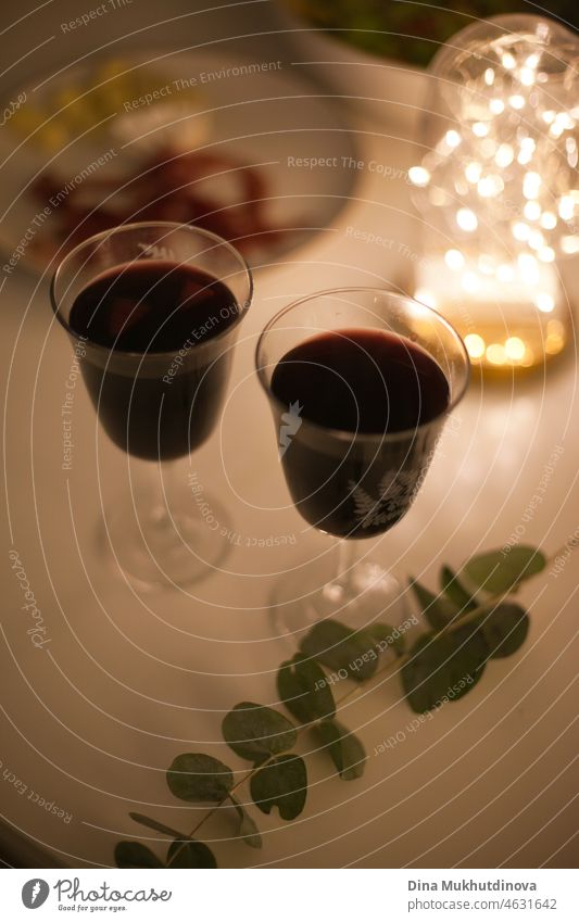 Two glasses of red wine with appetizers on a romantic candlelight date with festive lights drink alcohol table white restaurant beverage wineglass dinner bottle