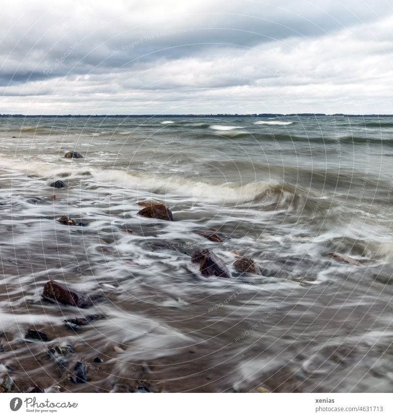 Movement of water on the beach of the Baltic Sea with overcast sky Water Waves Beach stones Sky Nature Lake coast Clouds motion blur Ocean Environment Stone