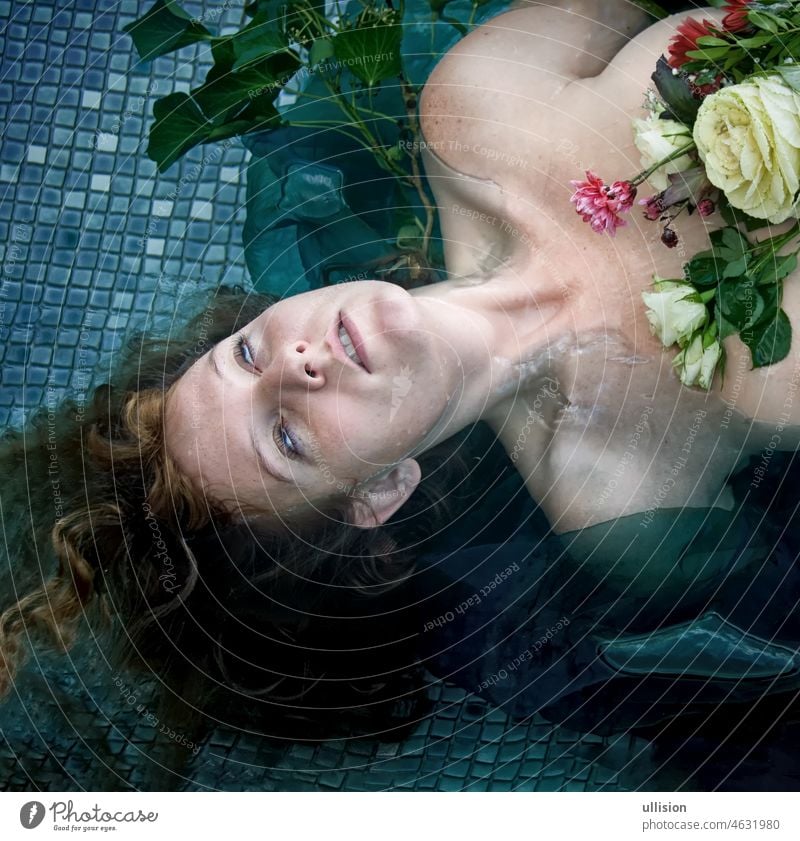 portrait of young sexy unhappy crazy woman lady Ophelia with red hair lies with the flowers with dead eyes in the water in the pool, copy space ophelia dying