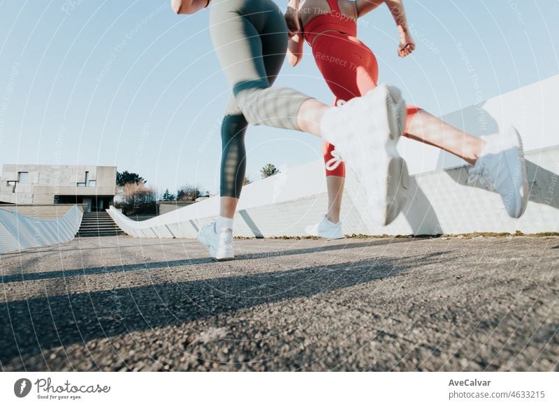 Two young fitness woman training running outdoors doing exercise wearing sportswear. Fitness girls working out together. Low angle image moving motion image. Healthy sport life