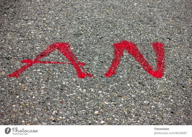 AN in red on Word Letters (alphabet) Characters Colour Red Asphalt Street Text Gray not off Deserted Clue Information