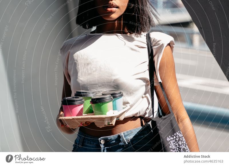 Crop black woman with drinks to go coffee carry street urban holder modern daytime city female african american ethnic style takeaway beverage lifestyle casual