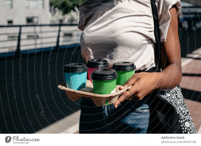 Black woman carrying tray with takeaway coffee beverage cardboard order disposable purchase female buyer drink to go street cup carton paper cup stroll service
