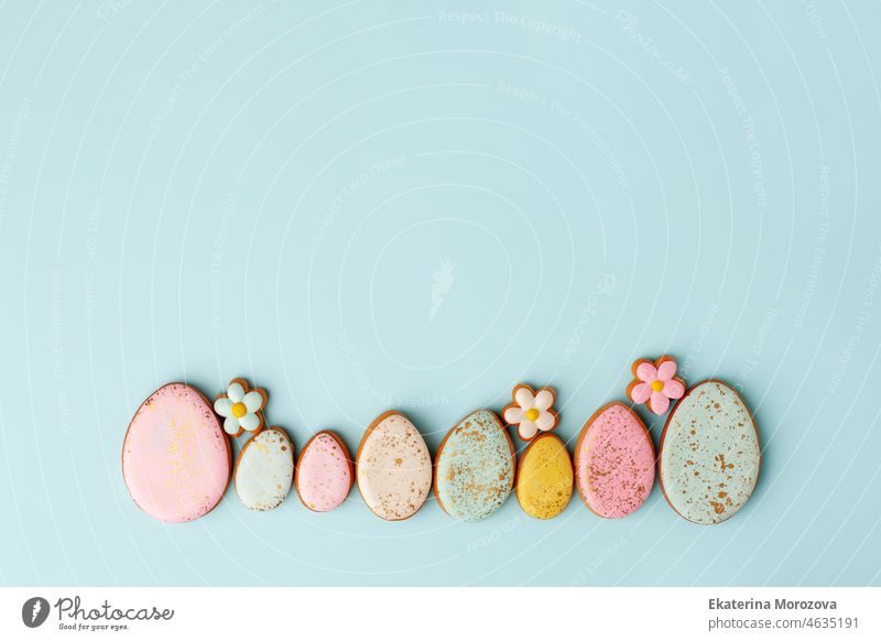 Sweets, pastry, gingerbread cookies for Easter table. Easter eggs and tender simple flowers on blue background top view copy space, spring seasonal holiday banner for your sute, flyer, coupon