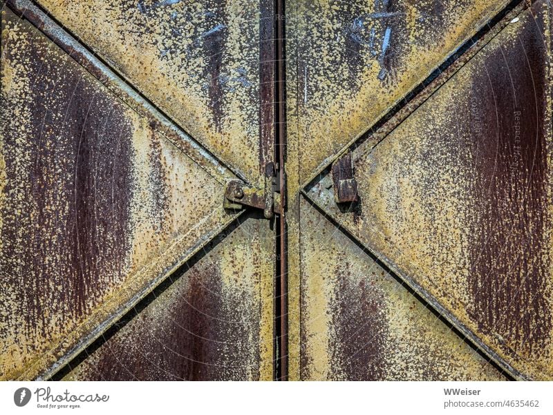 A large heavy locked iron door in a historic industrial facility Goal Geometry Heavy Large rusty diagonal Close-up Exterior shot out Deserted symmetric