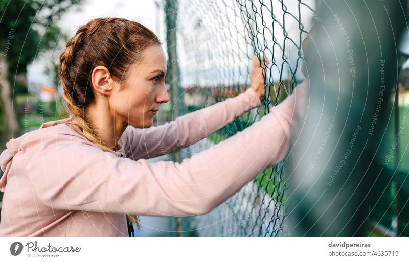 Serious portswoman with boxer braids leaning on a metal fence serious sportswoman profile girl power hard woman athlete defiant look active female hood portrait
