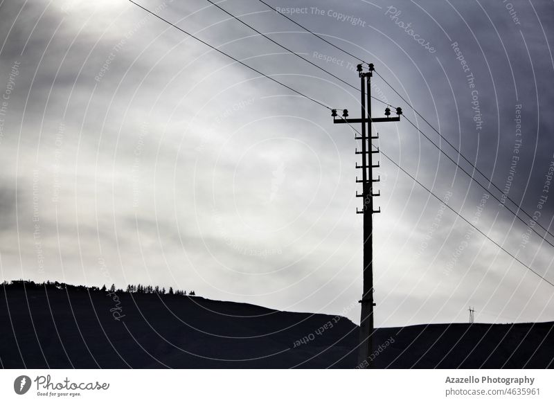 Industrial dramatic landscape with an electricity transmission pylon on horizon. atmosphere business cable clouds dark deserted deserted area dusk eco friendly