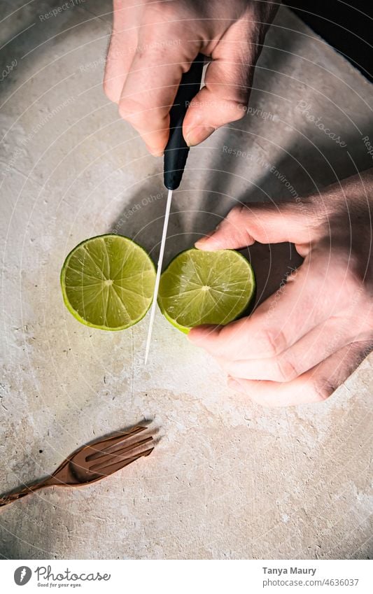 hands of a man cutting a lime in half with a knife Lemon juice Healthy Eating fruits Juice Vitamin Vitamin C Cold drink green lemons Colour photo colorful