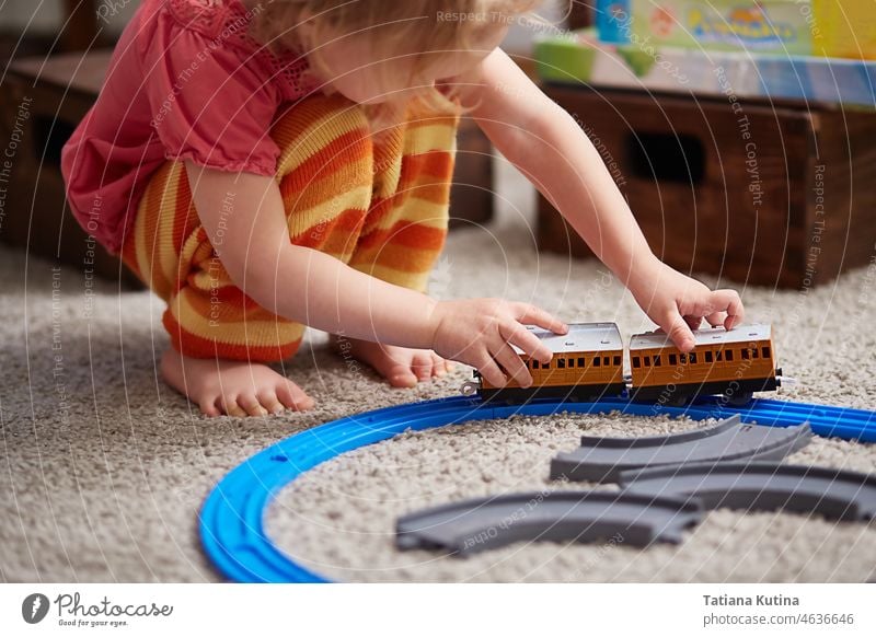 girl is playing with a train. Educational toys for preschool and kindergarten children. a girl is building a toy railway at home or in kindergarten learning