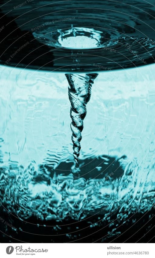 Vortex of overflowing water in rotating glass tube, water glass with rotating column of air, water tube with vortex storm from air, decorative kinetic technical sculpture.