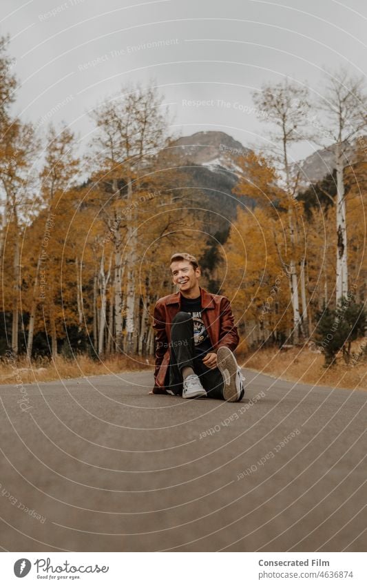 Teenager sitting in the middle of the road in the mountains of Colorado color fall autumn foliage travel adventure style fashion mens style mens fashion