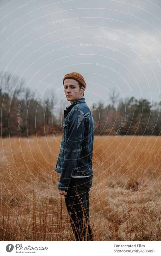 Man with street style walking through long grass in the woods looking over shoulder Jean jacket Style mens style mens fashion united kingdom europe skater style