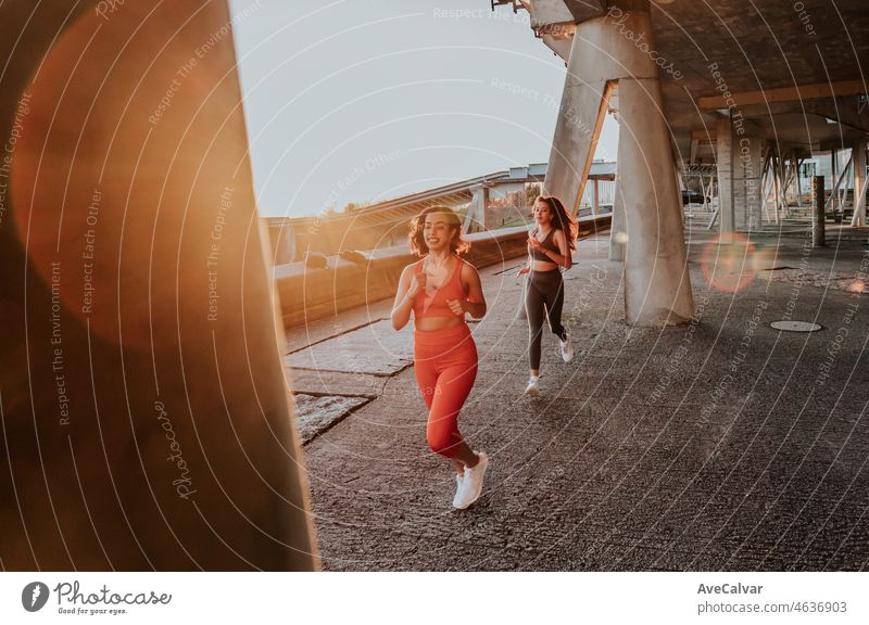 Two young sporty african woman running during sunset on an urban city scenario, hard contrast shadows, jogging during sunset. Healthy life new habits concept.Fun together motion image