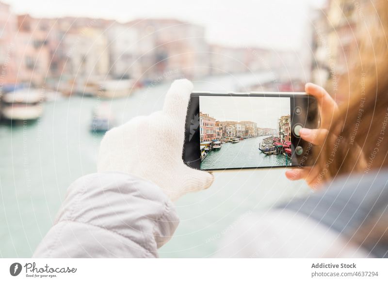 Unrecognizable woman photographing canal amidst colorful building on cloudy day in Venice take photo smartphone architecture vacation traveler trip boat sky