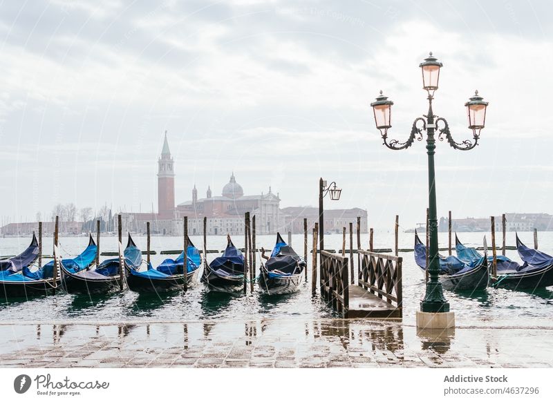 Gondolas moored on channel with historic basilica view gondola canal travel architecture heritage sightseeing city boat square tradition scenery cloudy sky