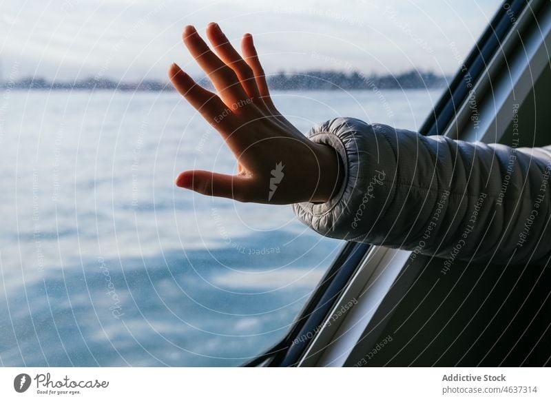 Crop female tourist touching window in boat woman cruise trip river voyage vacation tourism transport hand jacket warm clothes cloudy sky traveler passenger