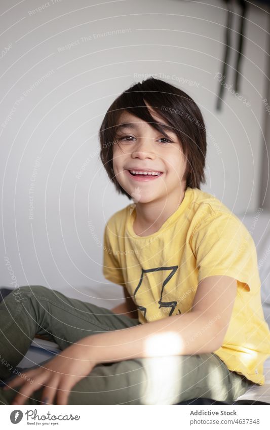 Ethnic boy sitting on light room kid smile childhood home appearance rest domestic chill glad ethnic apartment at home cute dark hair lounge calm casual sweet