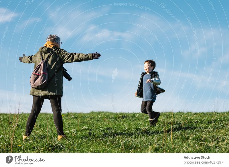 Grandmother outstretching arms to running boy on lawn grandmother grandson laugh fun nature arms outstretched happy joy cheerful carefree positive glade delight