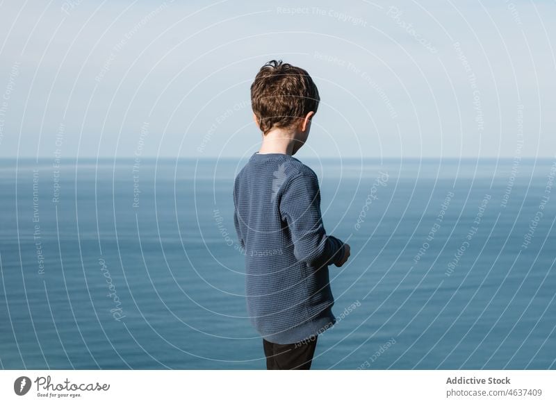 Boy admiring blue sea from coast boy admire freedom child seascape observe nature contemplate ripple kid environment childhood stand seaside shore water casual