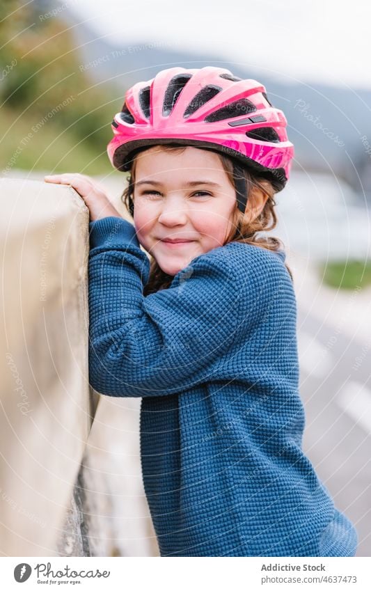 Girl in helmet standing near border girl kid hobby smile childhood street happy leisure spend time glad activity fence barrier stone safety summer active