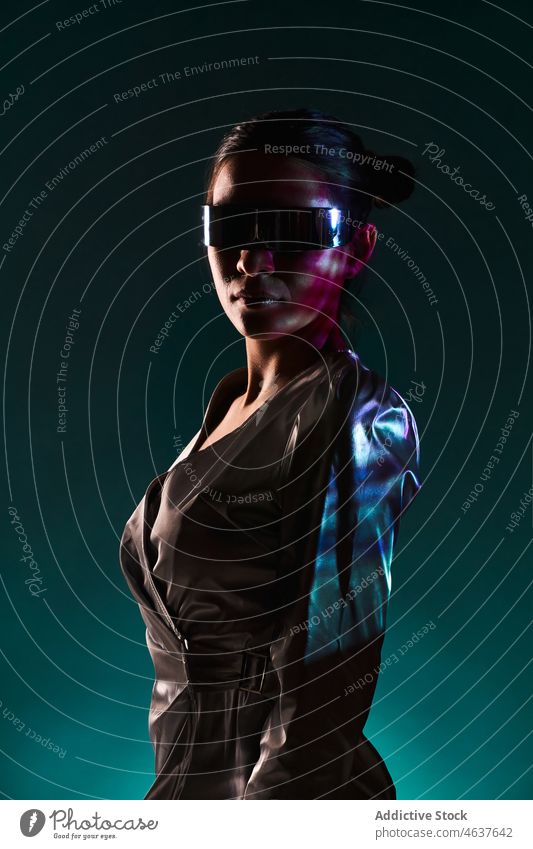 Fashionable ethnic lady in futuristic outfit standing in studio woman style self assured virtual reality model portrait fashion trendy experience confident