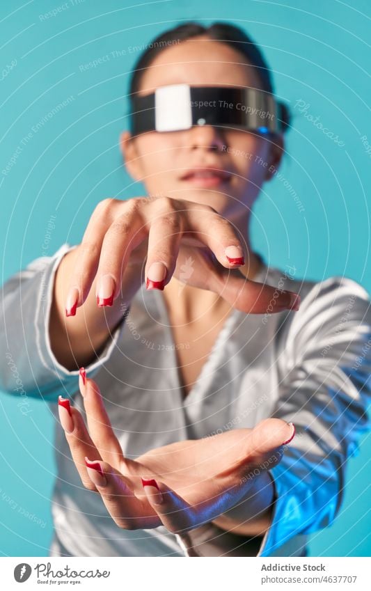 Young ethnic female touching invisible object while experiencing virtual reality in studio woman experience style cyberspace vr entertain digital augmented