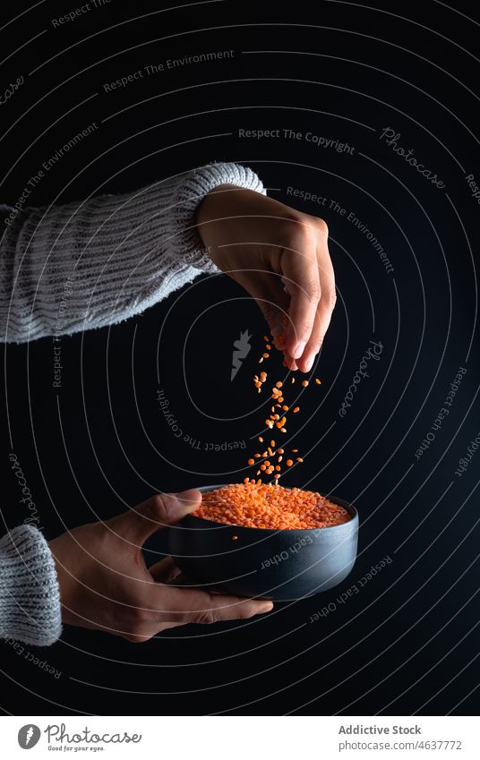 Anonymous person pouring red lentils legume culinary organic food raw uncooked bowl hand fresh natural prepare ingredient cuisine add product many light fill