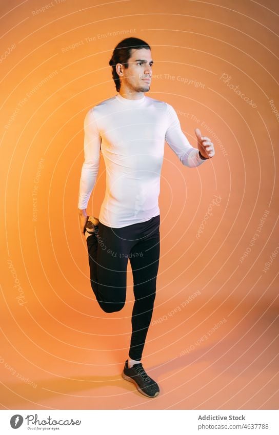 Young ethnic guy warming up before training against orange background man stretch workout wellness exercise warm up concentrate sport athlete sportsman fitness