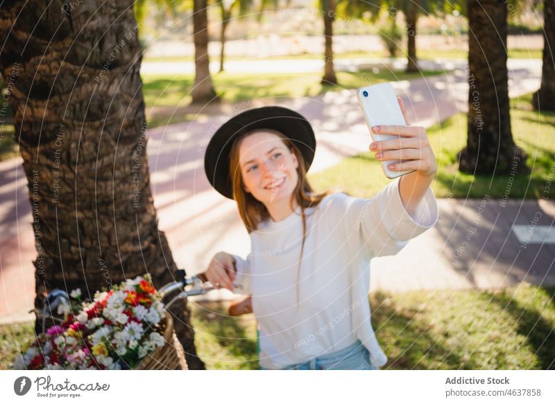 Woman taking a selfie against a bicycle with flowers woman smartphone park cyclist smile palm tropical summer female bike style self portrait positive cheerful