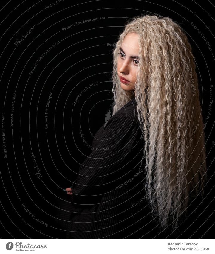 portrait of a young blonde girl with long curly hair long hair black background studio female beautiful woman cute attractive pretty happy youth adult beauty