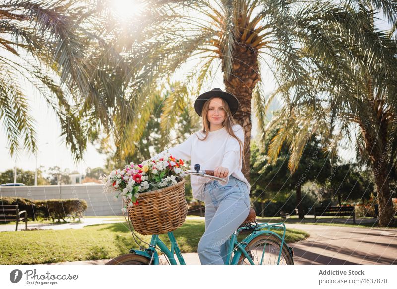 Young woman riding bicycle in park ride path flower weekend tropical style summer female casual bouquet young exotic fresh blossom alley way vehicle trendy