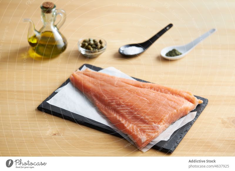Raw fish on cutting slate board with ingredients salmon raw fillet food kitchen cook culinary cuisine seasoning recipe seafood prepare uncooked pepper salt
