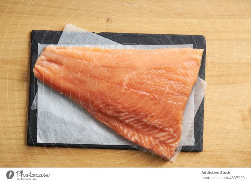 Raw fish on cutting slate board with ingredients salmon raw fillet food kitchen cook culinary cuisine seasoning recipe seafood prepare uncooked spoon slice