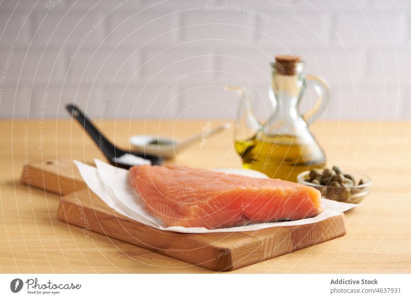Raw fish on cutting wooden board with ingredients salmon raw fillet food kitchen cook culinary cuisine seasoning slate recipe seafood prepare uncooked pepper