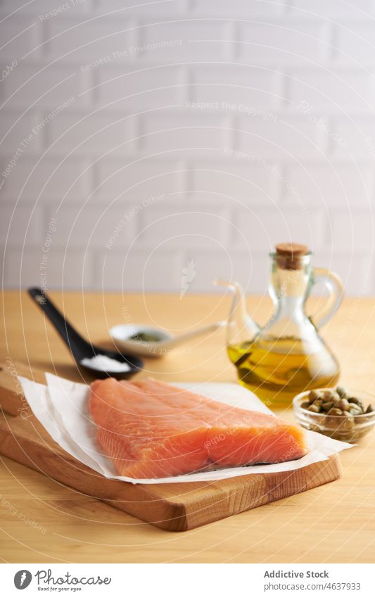 Raw fish on cutting wooden board with ingredients salmon raw fillet food kitchen cook culinary cuisine seasoning slate recipe seafood prepare uncooked pepper