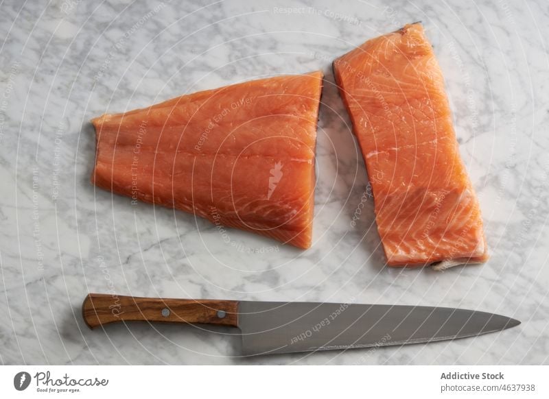 Raw fish on cutting marble board salmon raw fillet food ingredient kitchen cook culinary cuisine knife seasoning slate recipe seafood prepare uncooked spoon
