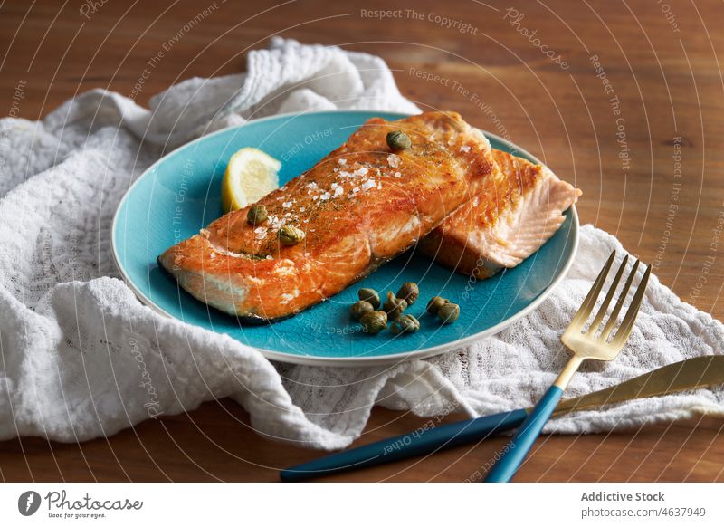 Delicious baked fish fillet with lemon salmon food steak seafood serve culinary cuisine eat dish plate meal dinner knife slice delicious tasty fork gourmet