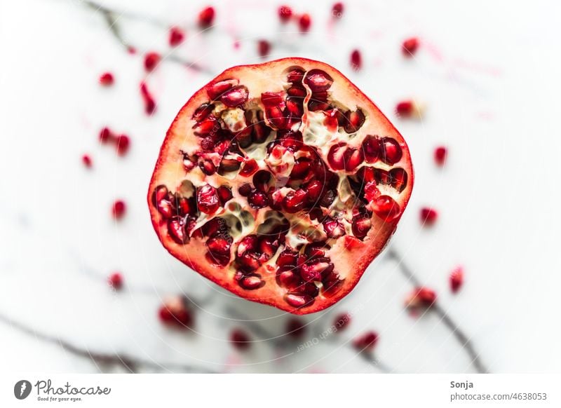 Top view of a halved pomegranate on a marbled background. Pomegranate plan Cross-section Mature Raw Red Fruit Organic Food Healthy Vitamin naturally cute Diet