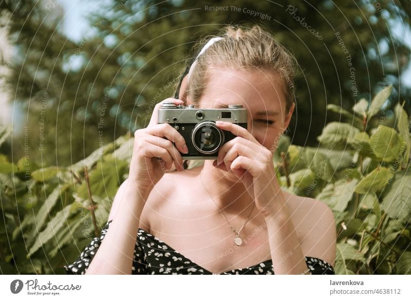 Young blonde female holding focusing vintage film camera outdoors woman equipment hand hobby lens lifestyle person photographer portrait retro technology young