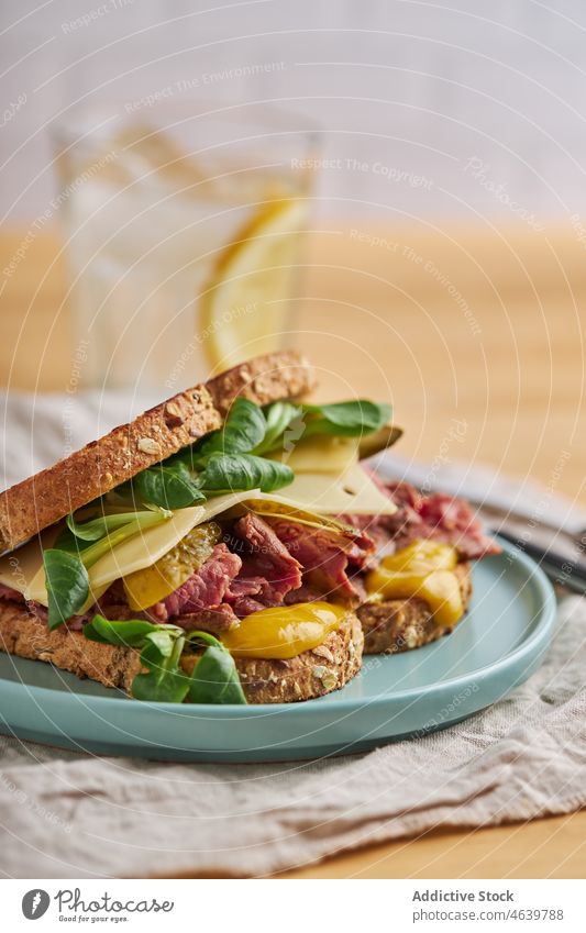 Delicious sandwich with egg and meat in toasted bread on plate food meal cheese delicious cuisine appetizing serve pastrami homemade pickles mustard ceramic