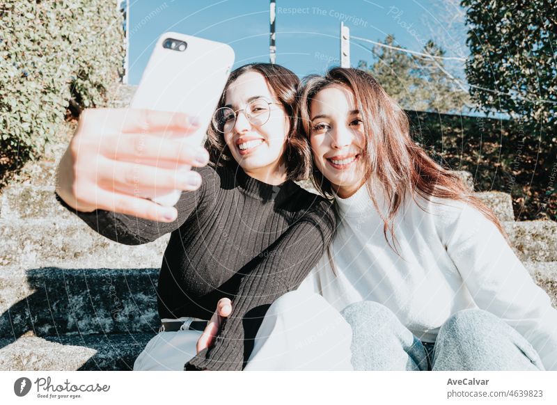 Girls taking a selfie while sitting on stairs, modern campus student youngsters recording a video for social networks while smiling. Good vibes and happiness concept. African girls at the university